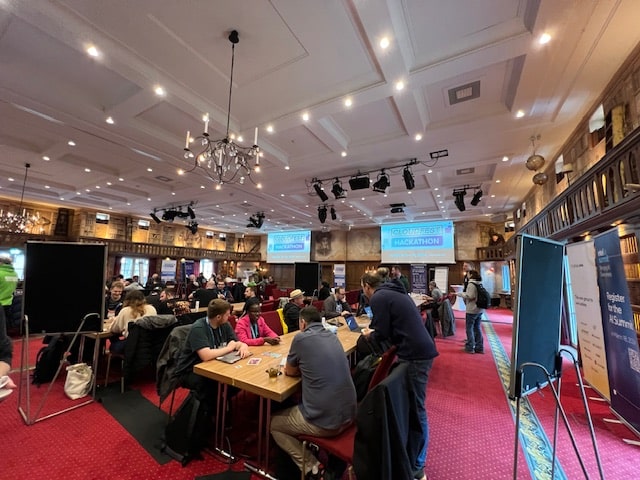 A photo of people sitting around tables at the Cloudfest Hackathon